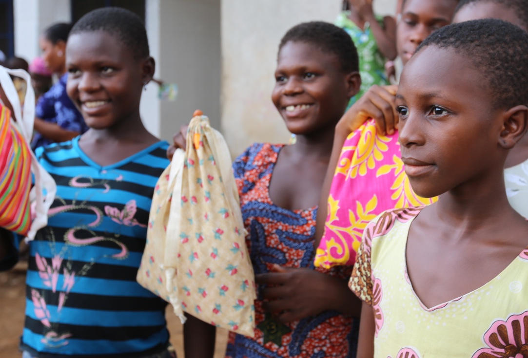 three young girls holding up DFG period kits, looking off camera