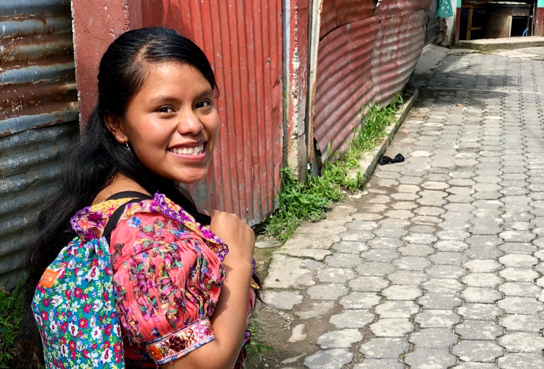girls smiling while looking over her shoulder with a back pack