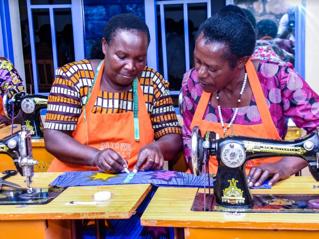 two women seated with one showing the other how to use the sewing machine
