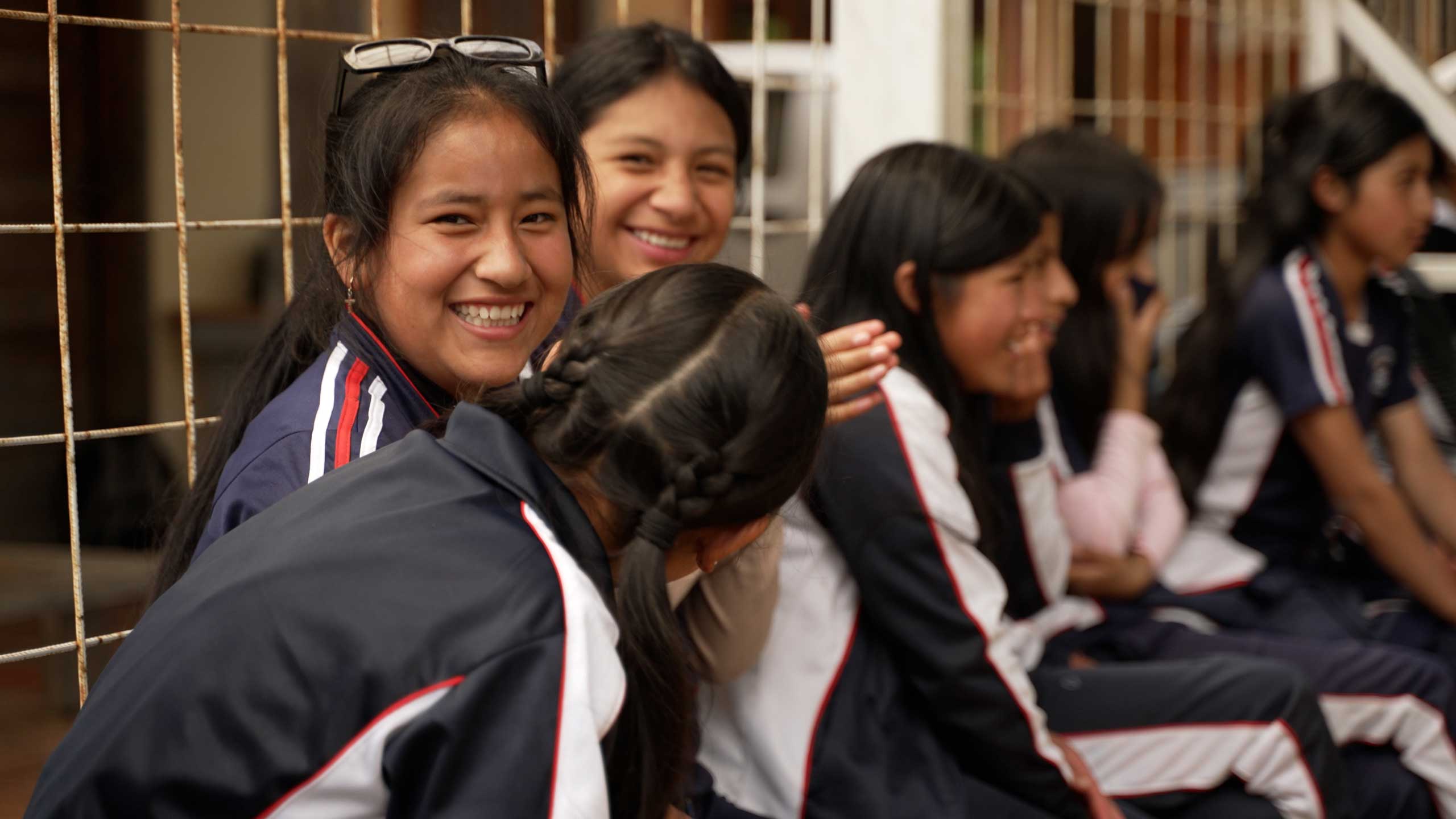 row of young girls sitting on a bench smiling and laughing
