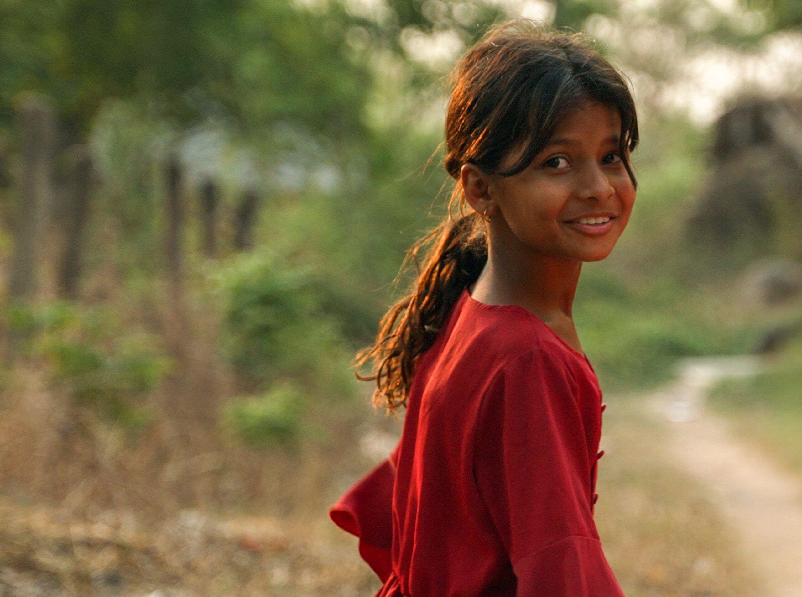 A girl in a red dress looking toward the camera